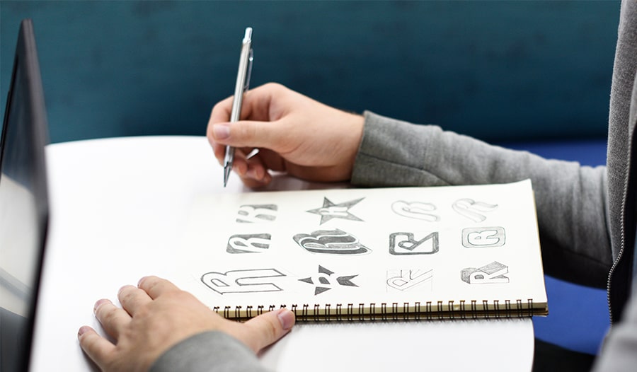 Mann skizziert auf Block Logos mit Stift in Hand